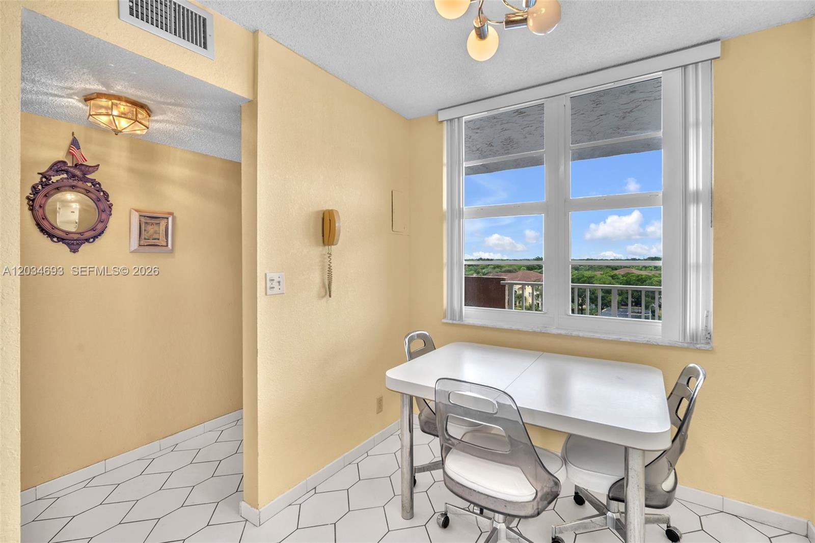 A dining area features a white table, clear chairs, yellow walls, and a large window — 250 Jacaranda Dr # 704, Plantation FL 33324, PLANTATION, FL