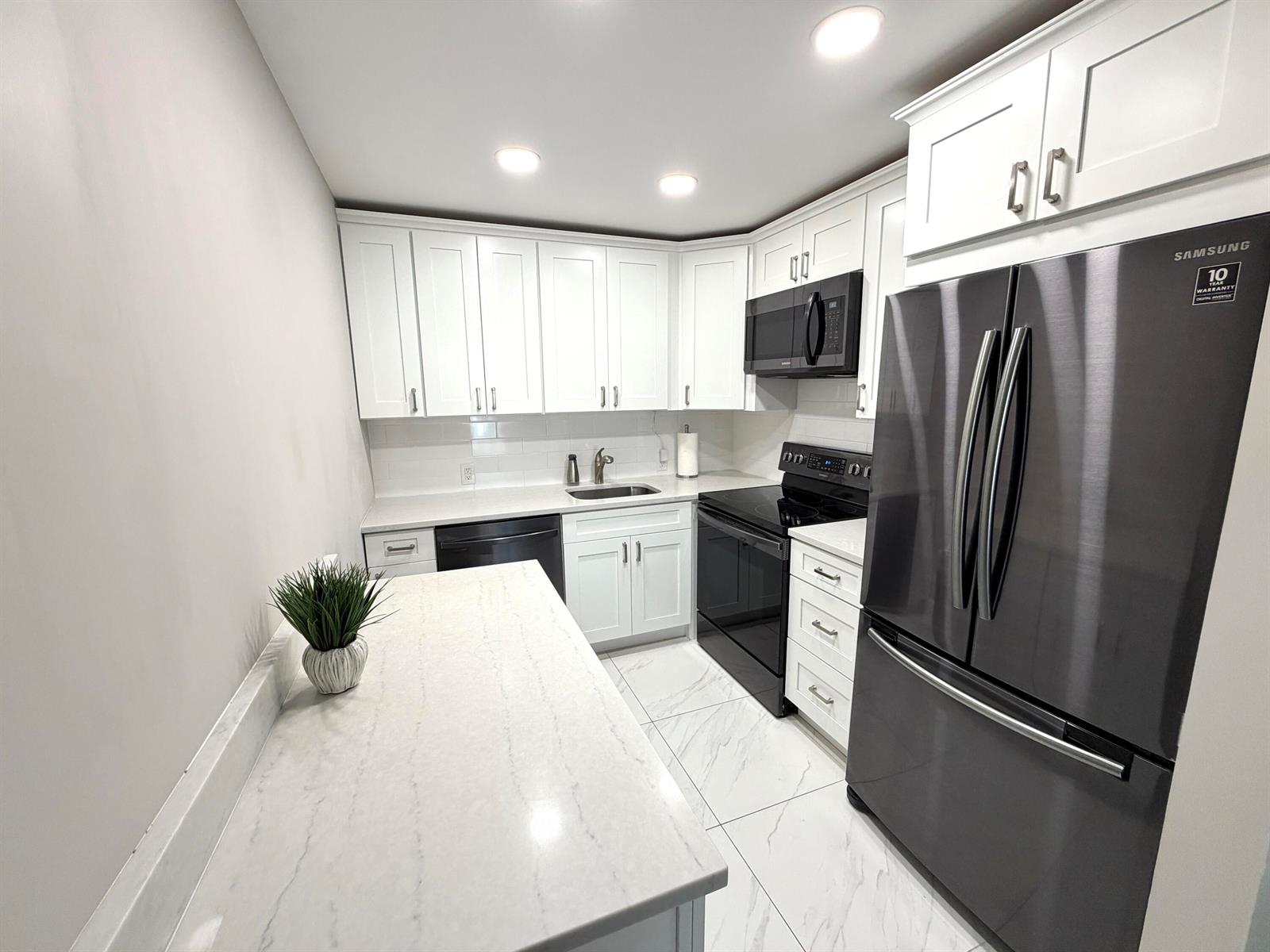 A modern kitchen features white cabinets, stainless steel appliances, and a white marble-patterned countertop — 101 Dorset C, Boca Raton FL 33434, BOCA RATON, FL