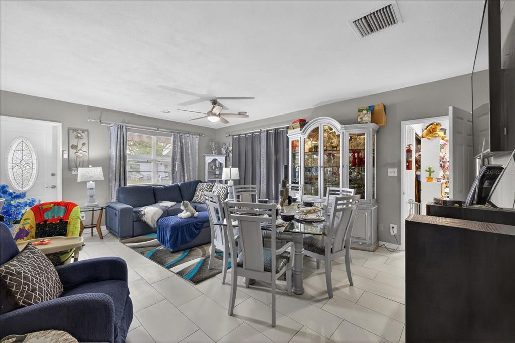 A living and dining room area features a blue sofa, glass-topped table, and tile flooring — 611 N BRADFORD AVENUE, TAMPA, FL