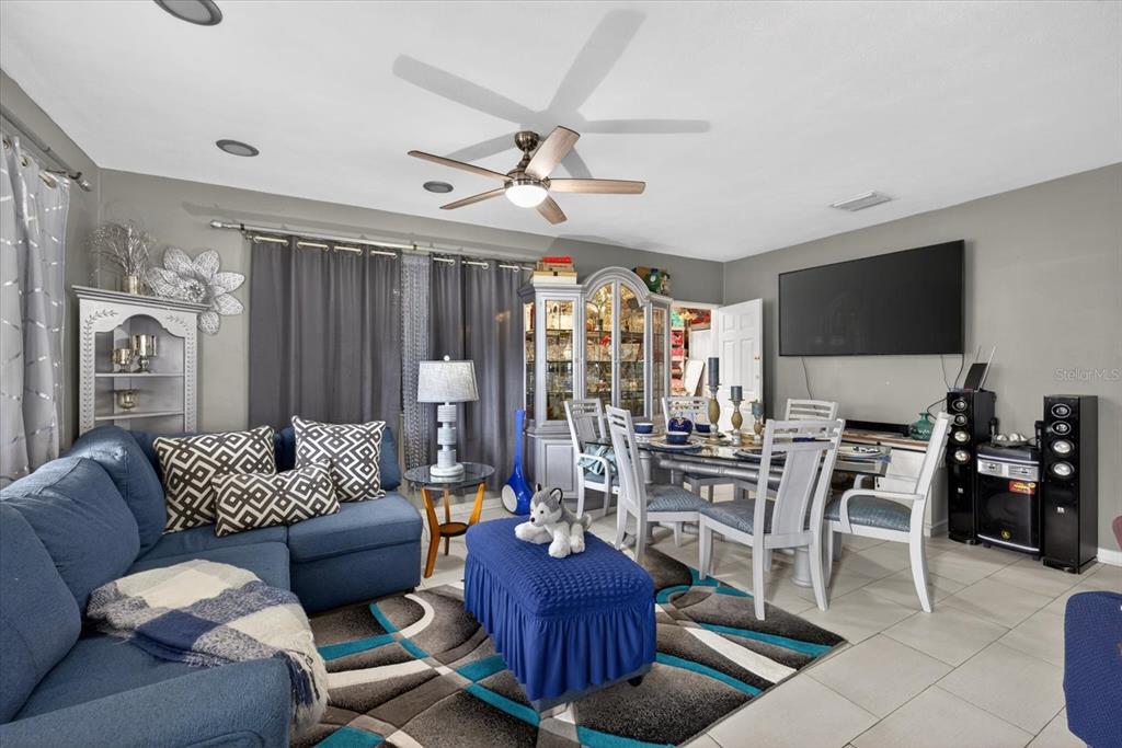 A living and dining area features a blue sectional sofa, a matching ottoman, and furniture — 611 N BRADFORD AVENUE, TAMPA, FL