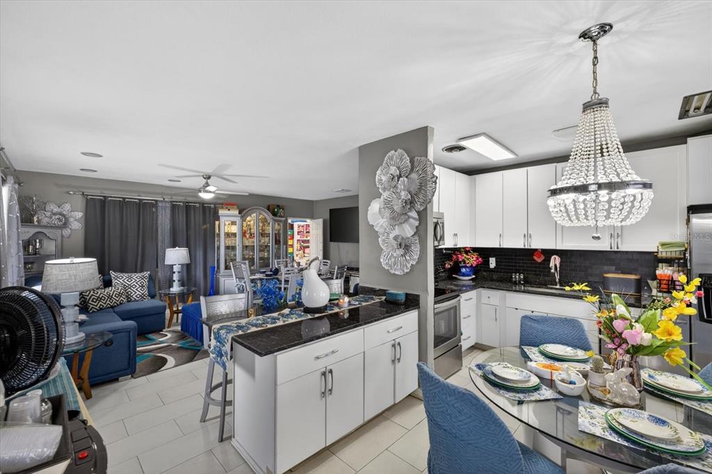 An open-concept kitchen and living area featuring white cabinets, dark countertops, and blue furniture — 611 N BRADFORD AVENUE, TAMPA, FL