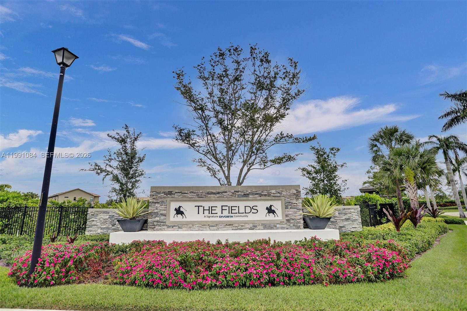A stone monument sign for The Fields community sits behind a bed of pink flowers — 4814 Jumping Way, Lake Worth FL 33467, LAKE WORTH, FL