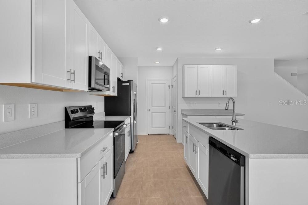 A modern kitchen features white cabinets, stainless steel appliances, and a large central island — 12411 GUST COURT, HUDSON, FL