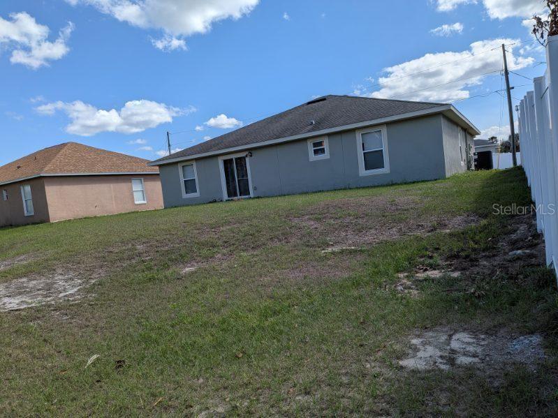 The exterior of a gray house with a backyard and a white vinyl fence — 187 CONCH DRIVE, POINCIANA, FL