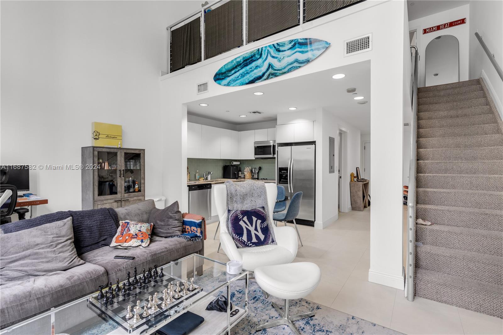 A living room with a grey sofa, white armchair, and a kitchen visible in the background — 1060 Brickell Ave # 409, Miami FL 33131, MIAMI, FL