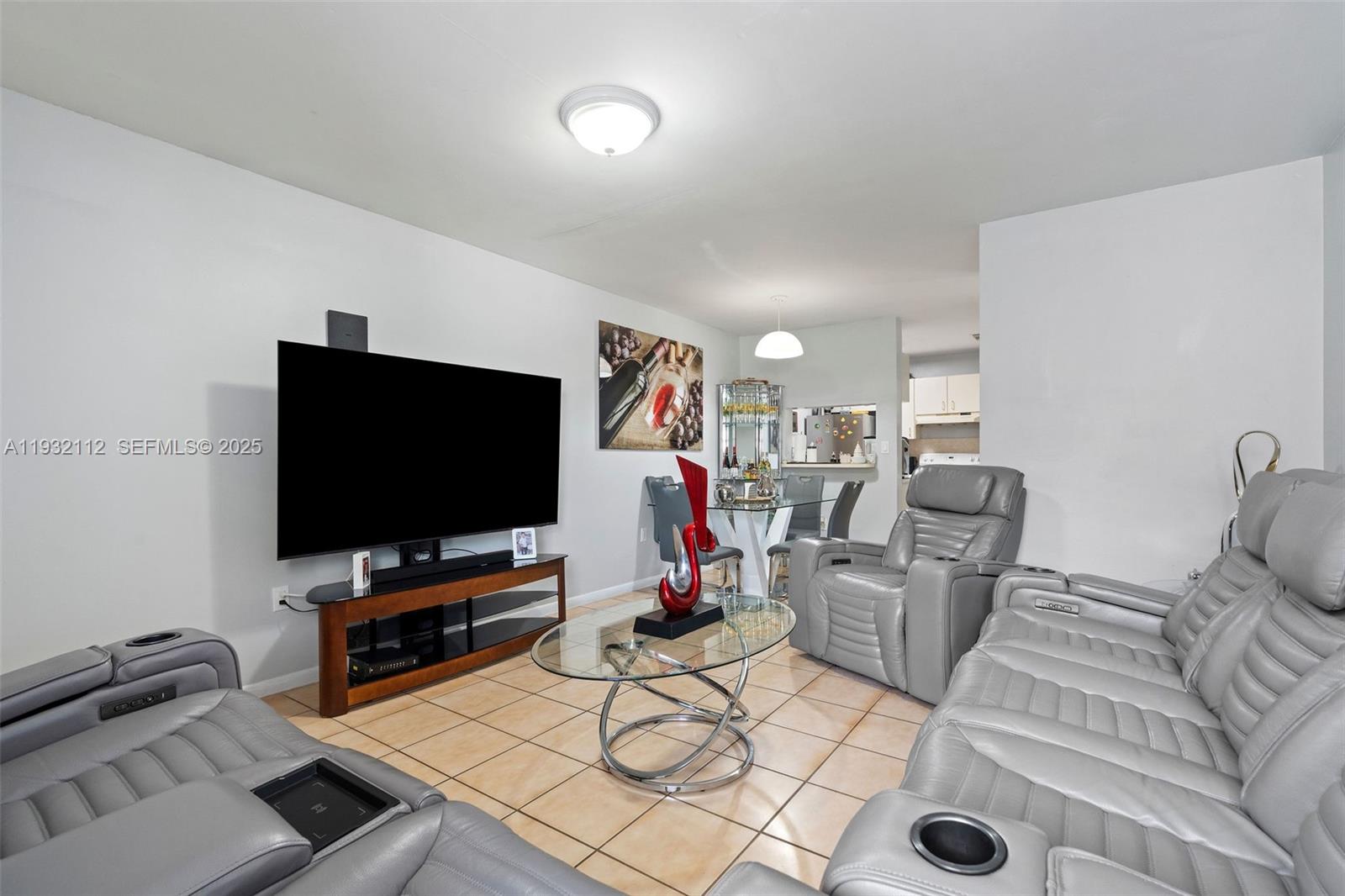 A living room features gray leather reclining furniture, a glass coffee table, and tile flooring — 7111 SW 129th Ave # 6, Miami FL 33183, MIAMI, FL