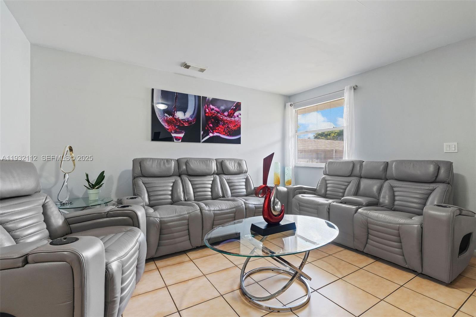 A living room features gray leather reclining furniture, a glass coffee table, and tile flooring — 7111 SW 129th Ave # 6, Miami FL 33183, MIAMI, FL