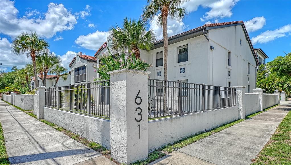 A multi-story white apartment building with a metal fence and palm trees in front — 631 N ORANGE AVENUE UNIT 108, SARASOTA, FL
