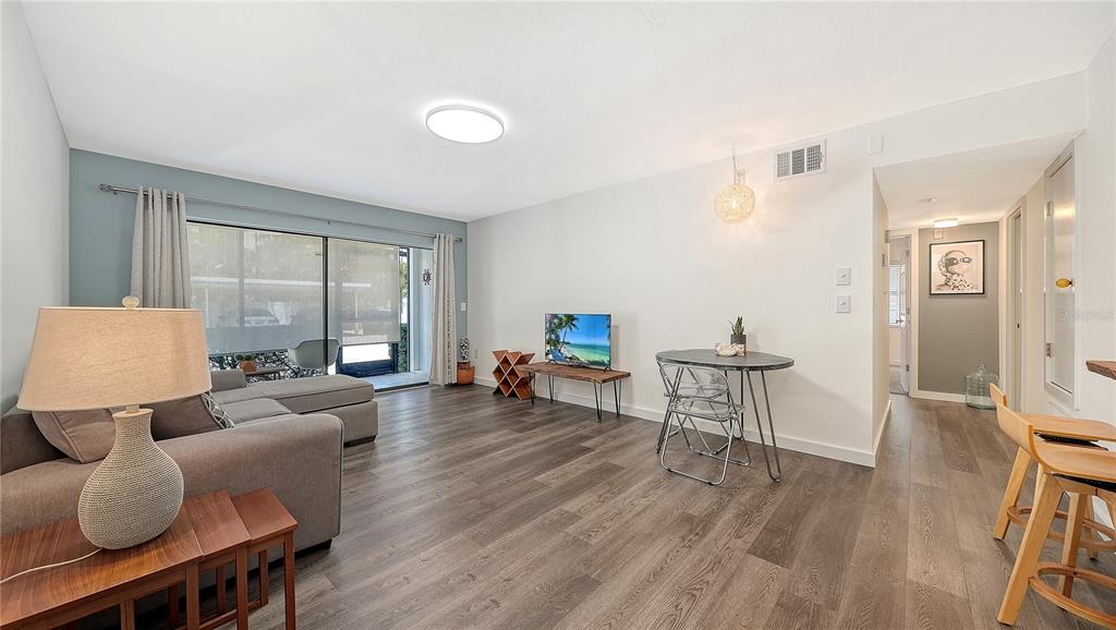 A living room features gray wood-look flooring, a sectional sofa, a small dining table, and sliding doors — 631 N ORANGE AVENUE UNIT 108, SARASOTA, FL