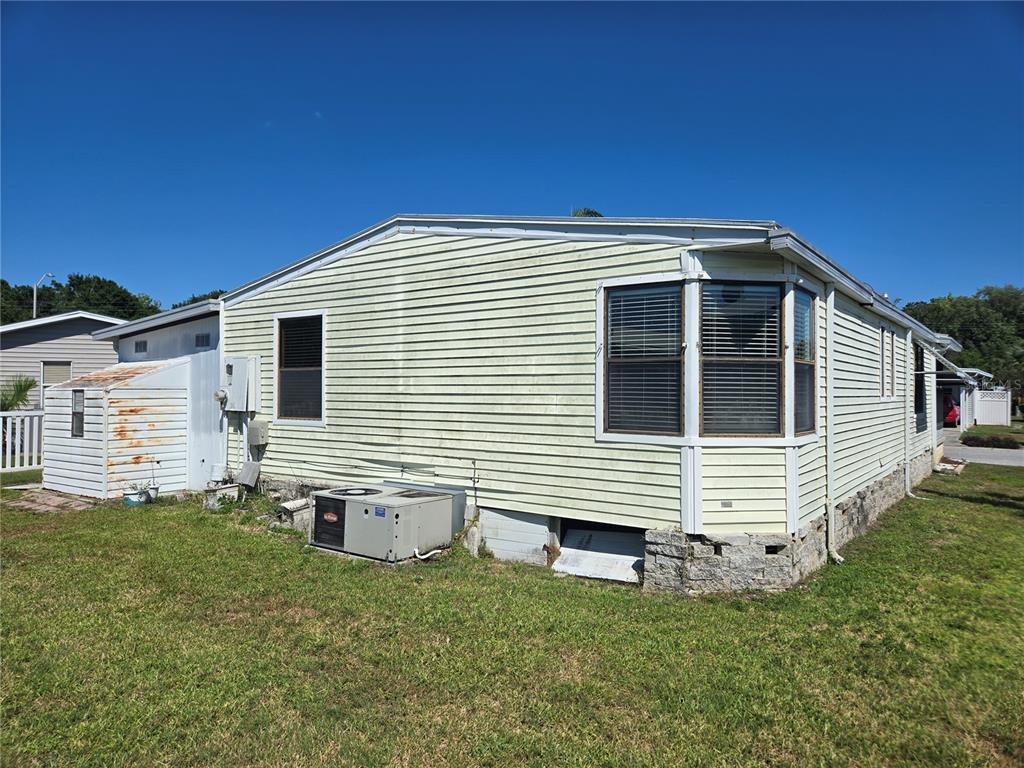 The exterior of a light-colored manufactured home features vinyl siding, a bay window, and skirting — 68 PELICAN DRIVE S, OLDSMAR, FL
