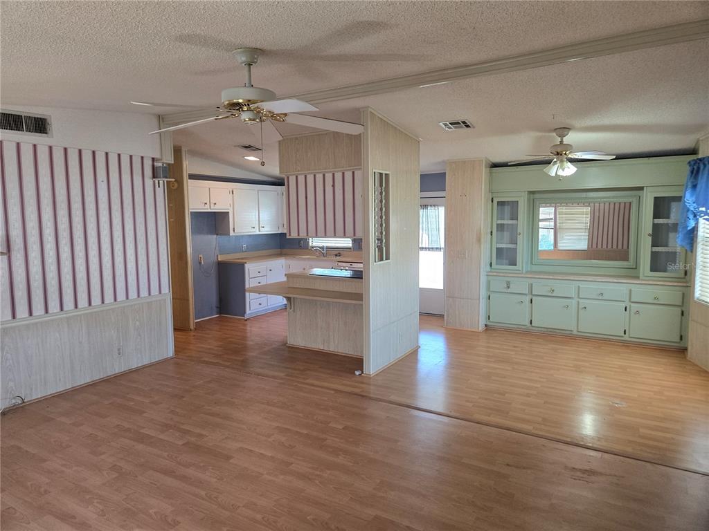 A kitchen and dining area features wood-look flooring, light wood paneling, and a ceiling fan — 68 PELICAN DRIVE S, OLDSMAR, FL