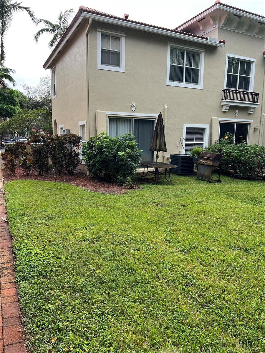 The exterior of a two-story tan stucco townhouse features a small patio and lawn — 3116 Merrick Terrace # 3116, Margate FL 33063, MARGATE, FL