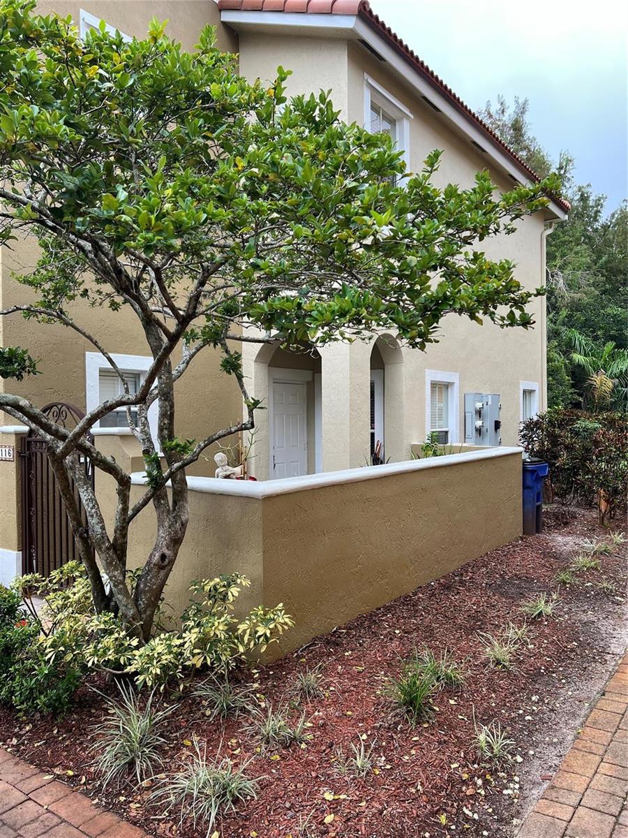 A two-story tan stucco building features a low courtyard wall and a large tree — 3116 Merrick Terrace # 3116, Margate FL 33063, MARGATE, FL