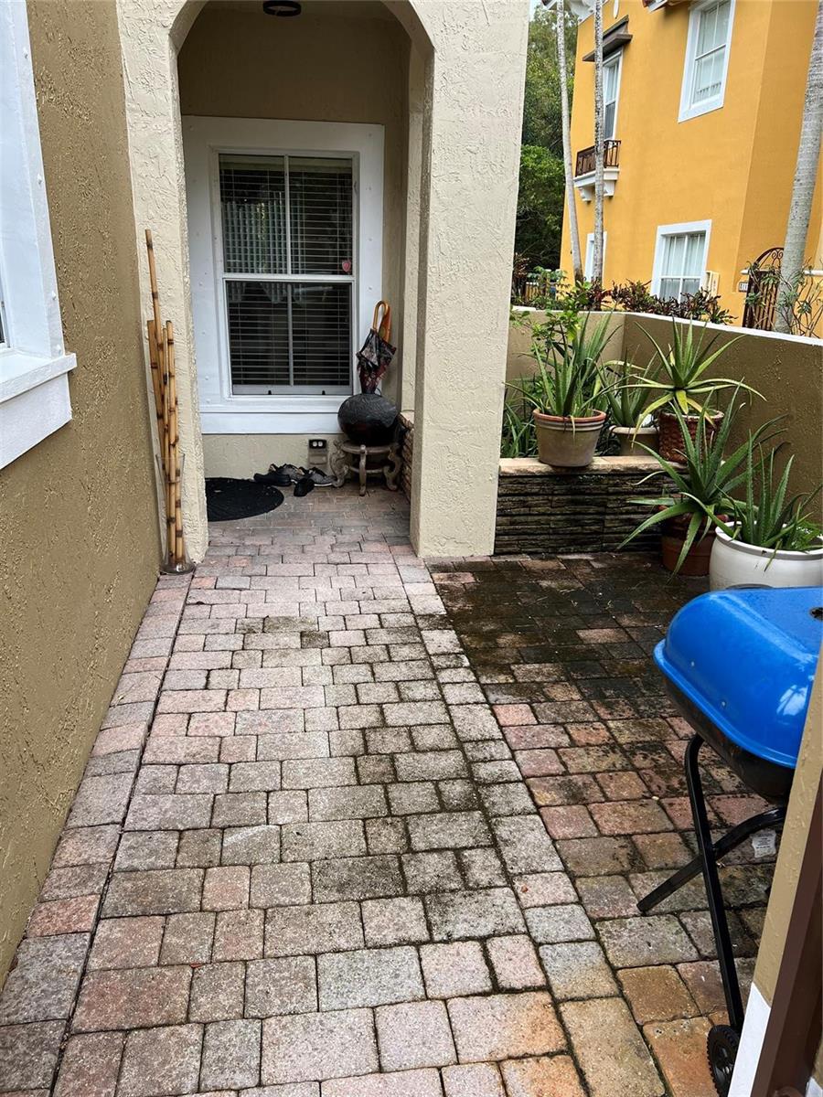 A paved patio area features a covered entryway, potted plants, and a blue charcoal grill — 3116 Merrick Terrace # 3116, Margate FL 33063, MARGATE, FL