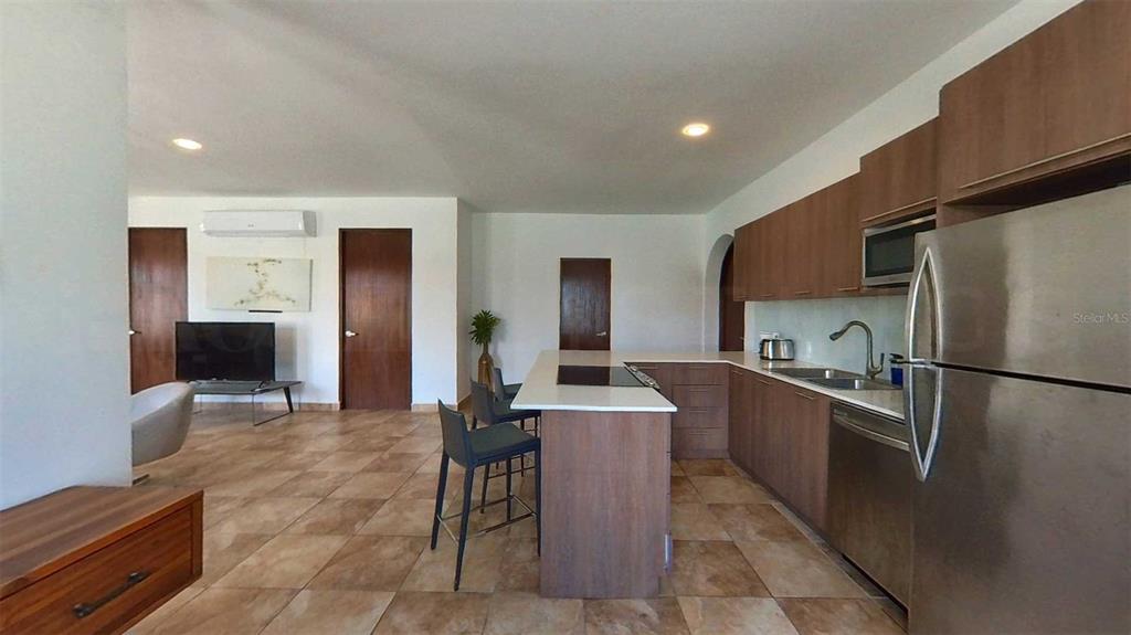 An open-concept kitchen with wood cabinets and a white island overlooks a living area — 209 SAN FRANCISCO STREET, SAN JUAN, PR