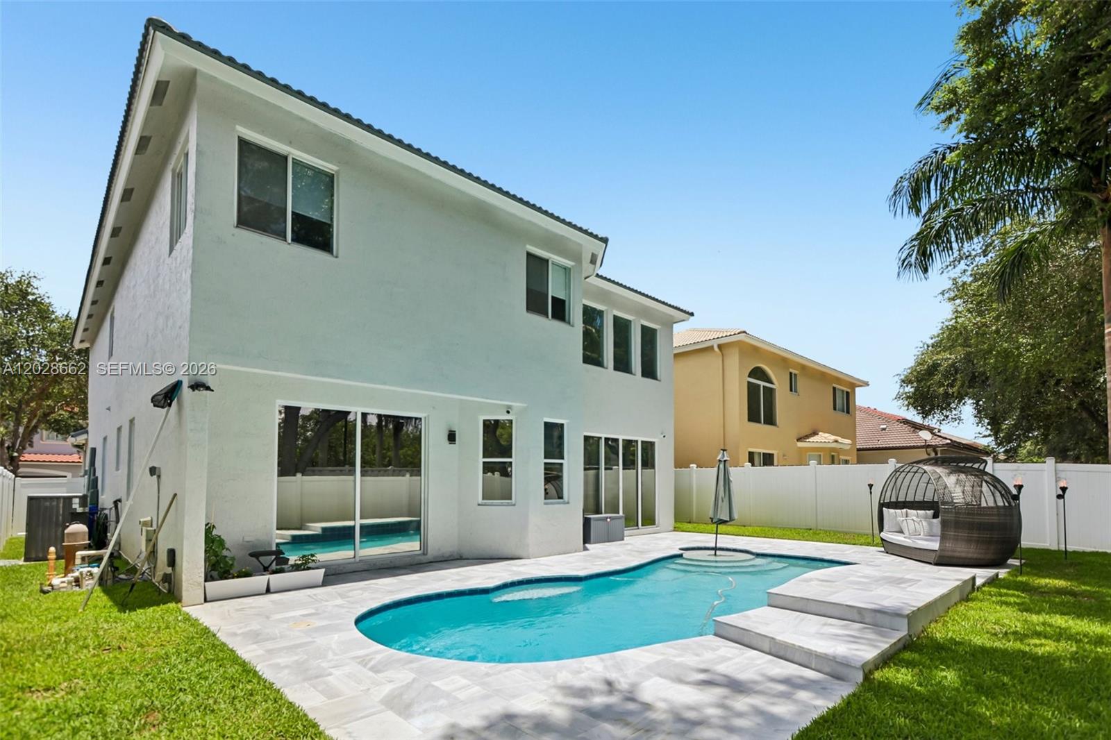 The backyard features a swimming pool with a stone patio and a white fence — 13370 SW 32nd St, Miramar FL 33027, MIRAMAR, FL