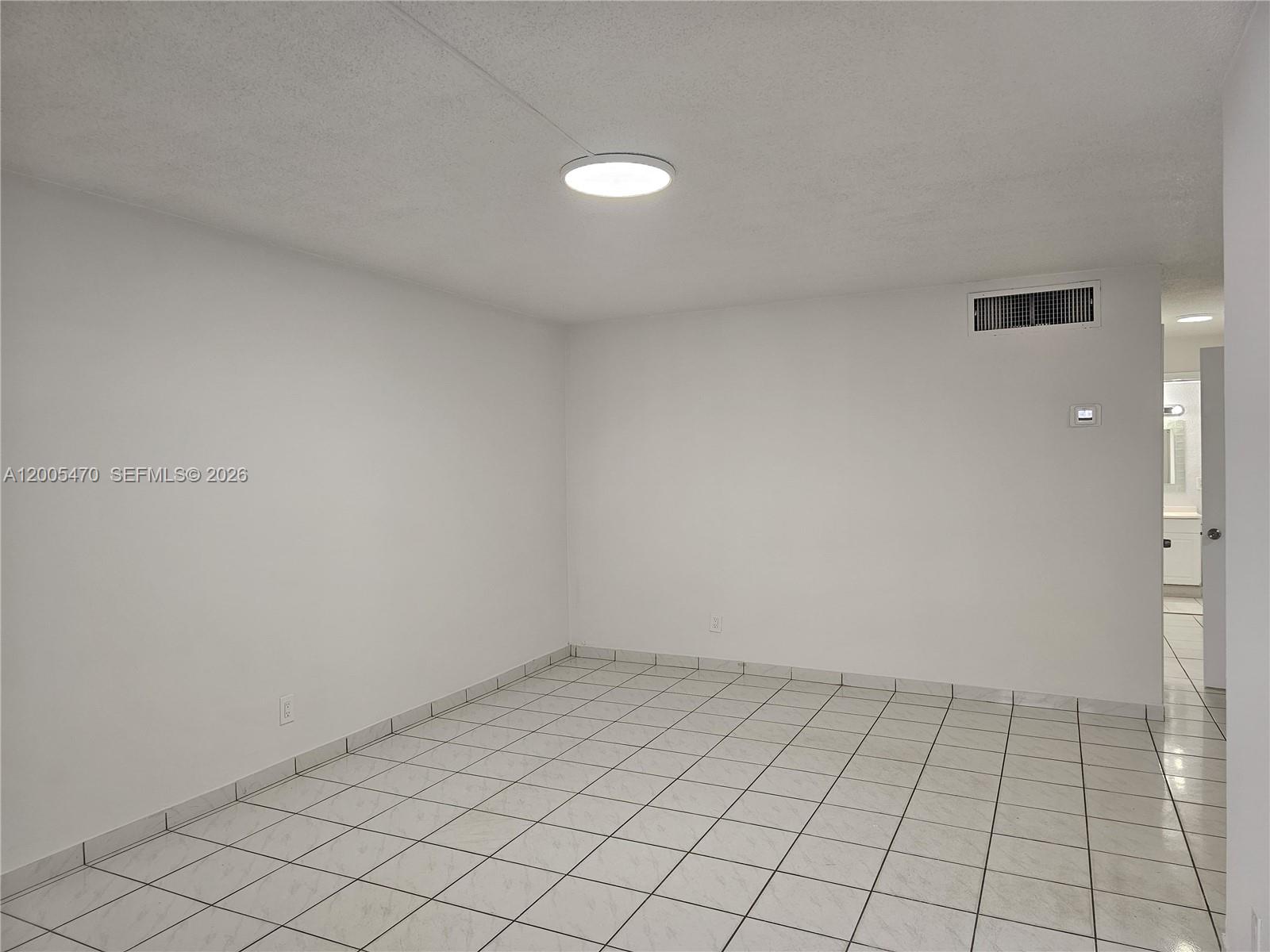 A sparsely furnished room features white walls, a tiled floor, and a ceiling light fixture — 1719 Wiley St # 2, Hollywood FL 33020, HOLLYWOOD, FL