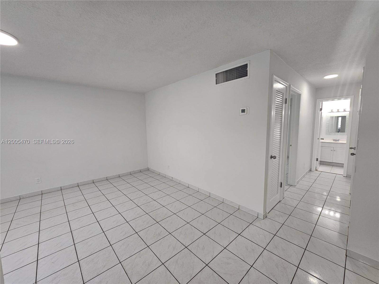 An empty room with white walls and light-colored tiled flooring leads to a bathroom — 1719 Wiley St # 2, Hollywood FL 33020, HOLLYWOOD, FL