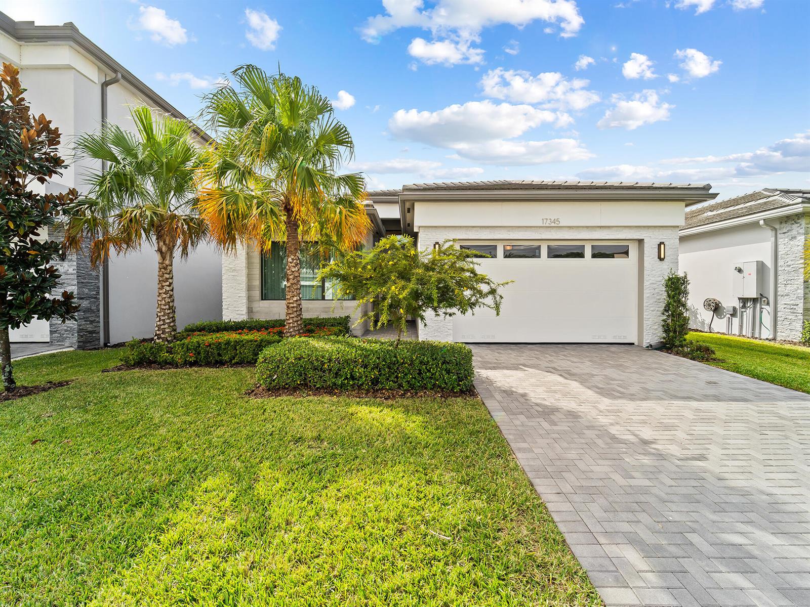 A modern single-story house features a white brick facade, a paved driveway, and palm trees — 17345 Sea Blossom Way, Boca Raton FL 33496, BOCA RATON, FL
