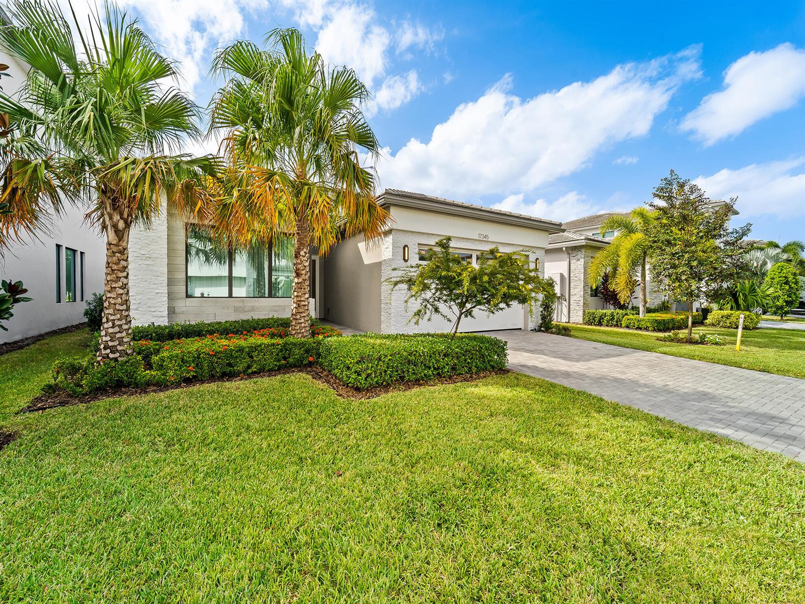 A single-story house with a white stone facade, palm trees, and a paved driveway — 17345 Sea Blossom Way, Boca Raton FL 33496, BOCA RATON, FL