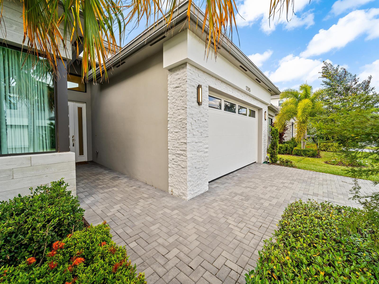A modern house exterior features a white garage door, stone accents, and a paved driveway — 17345 Sea Blossom Way, Boca Raton FL 33496, BOCA RATON, FL