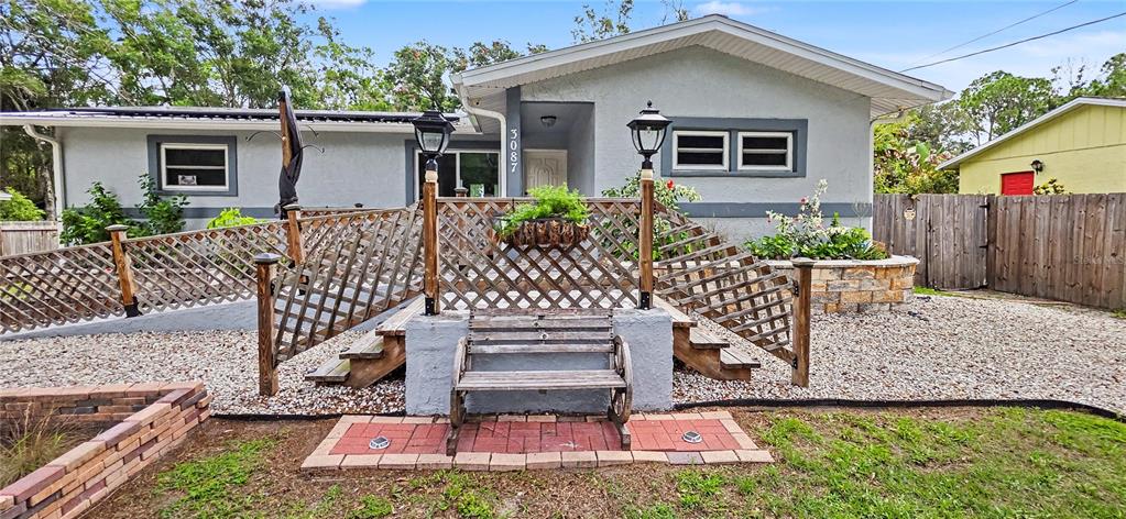 A gray house features a wooden deck with lattice railings, a bench, and gravel landscaping — 3087 DUANE AVENUE, OLDSMAR, FL