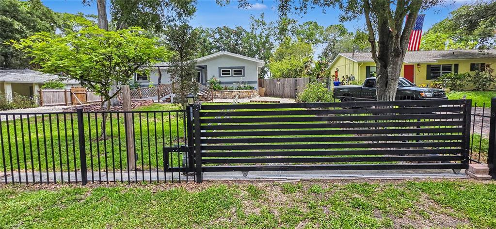 A black horizontal slat sliding gate stands in front of a residential property — 3087 DUANE AVENUE, OLDSMAR, FL
