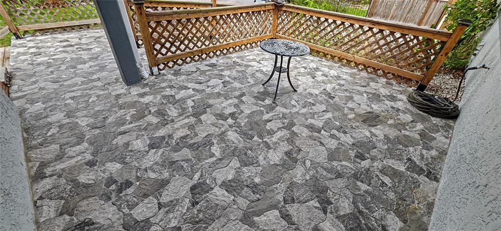 A patio features gray stone-look pavers, a wooden lattice railing, and a small metal table — 3087 DUANE AVENUE, OLDSMAR, FL