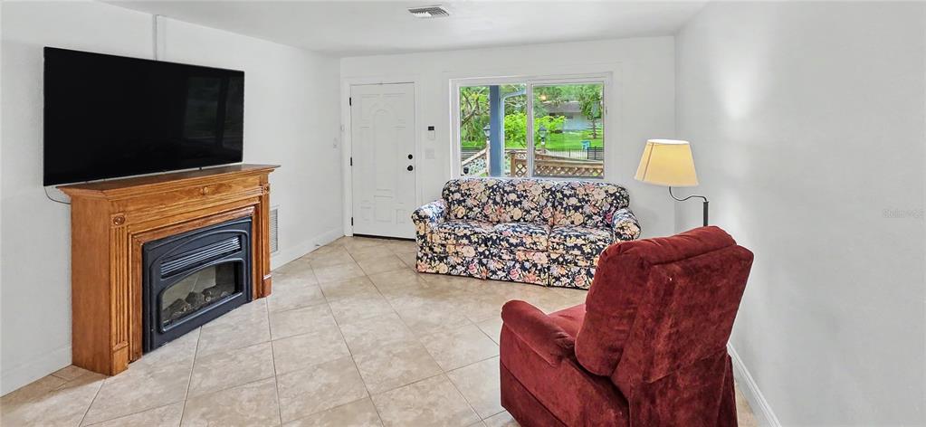 A living room features a fireplace, a floral sofa, a red recliner, and tile flooring — 3087 DUANE AVENUE, OLDSMAR, FL