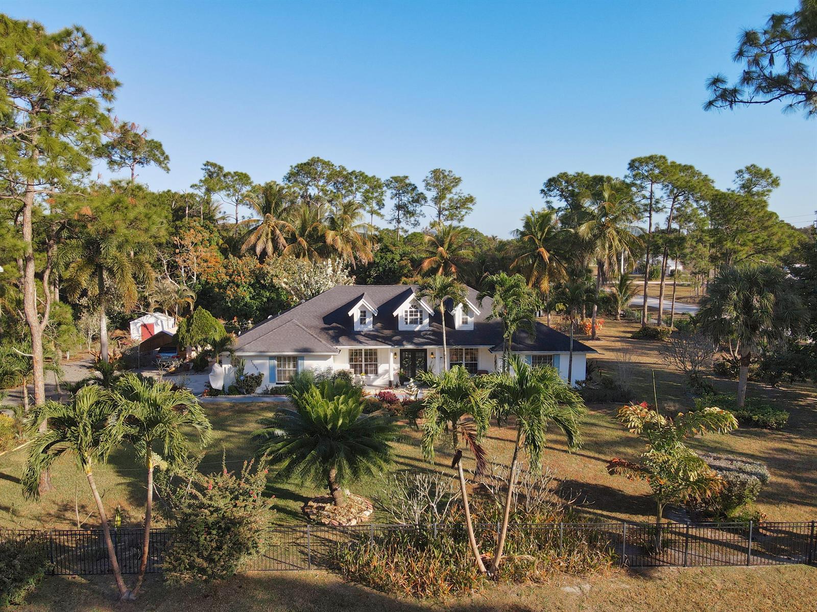 An aerial view of a white house with a dark roof surrounded by palm trees — 15049 85th Road N, Loxahatchee FL 33470, LOXAHATCHEE, FL