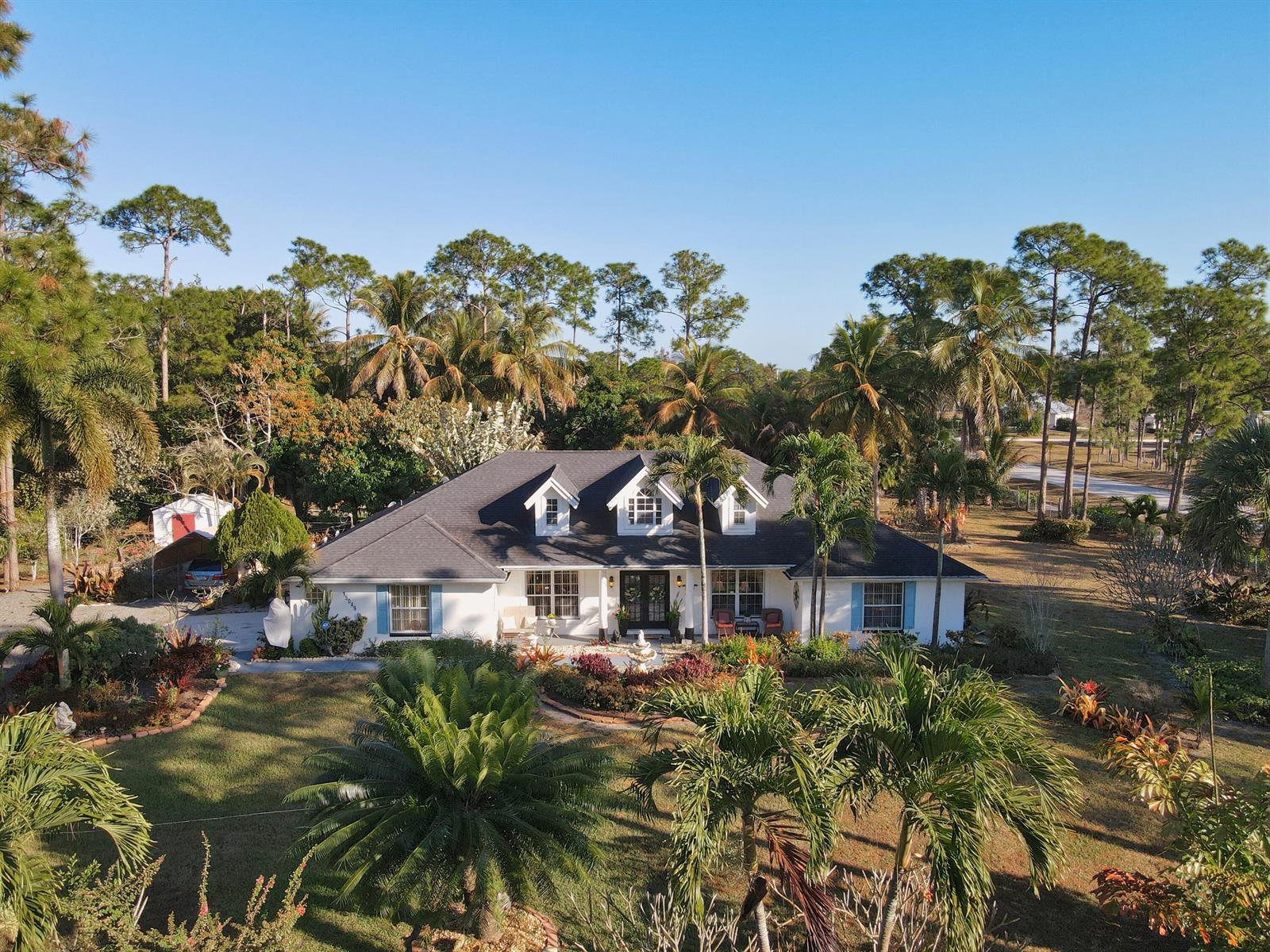 An aerial view of a white single-story house with blue shutters and a dark roof — 15049 85th Road N, Loxahatchee FL 33470, LOXAHATCHEE, FL
