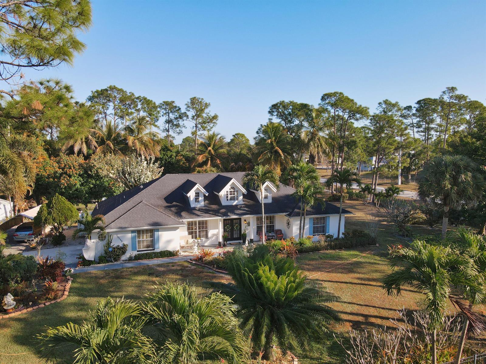 An aerial view of a white single-story house with a dark roof and dormer windows — 15049 85th Road N, Loxahatchee FL 33470, LOXAHATCHEE, FL