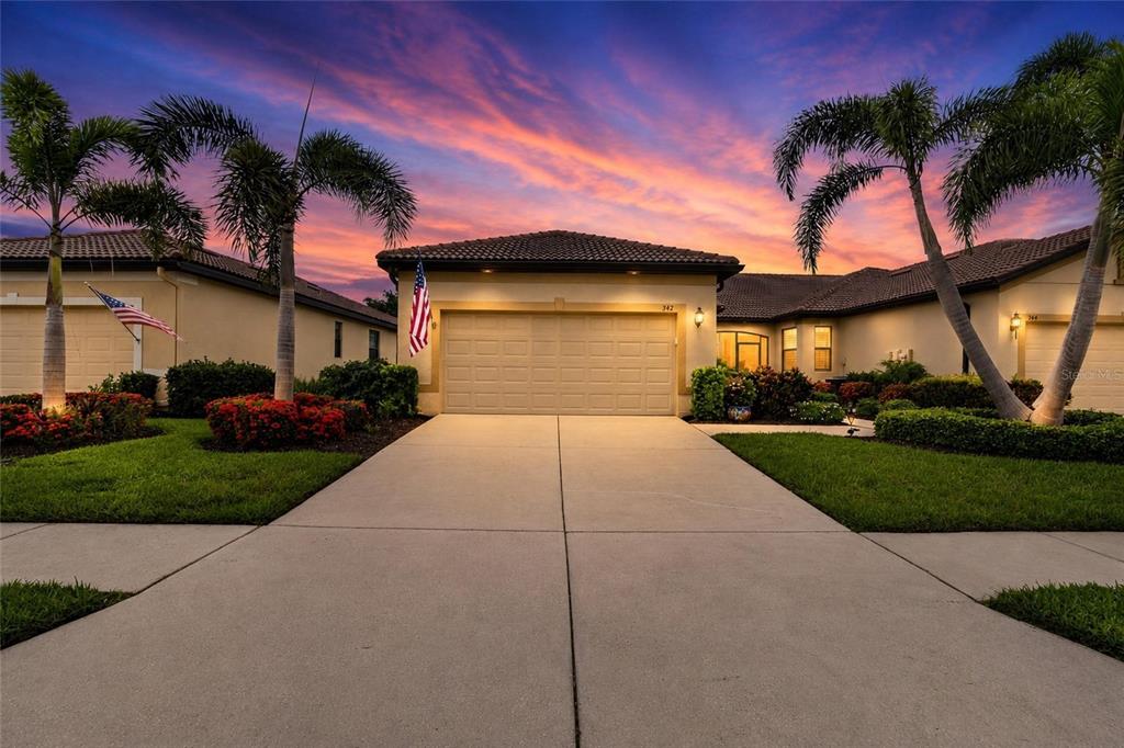 A single-story house with a beige exterior, a two-car garage, and palm trees at sunset — 342 BLUEWATER FALLS COURT, APOLLO BEACH, FL