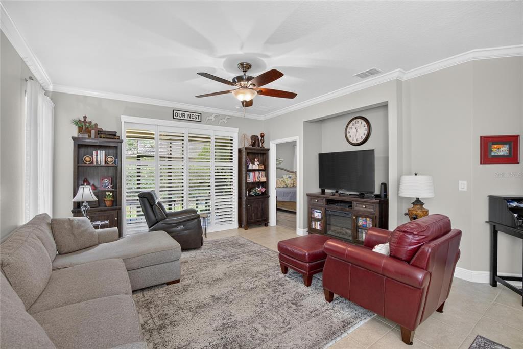 A living room features a gray sectional, a red leather chair, and a television console — 342 BLUEWATER FALLS COURT, APOLLO BEACH, FL