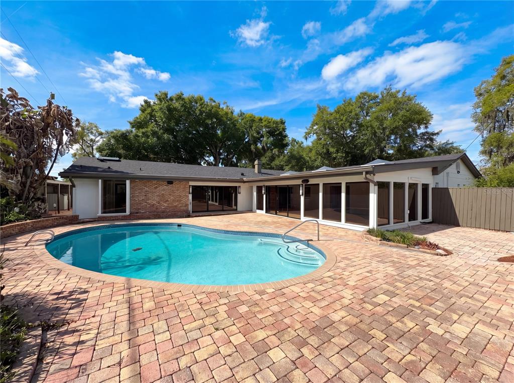 A backyard features a kidney-shaped swimming pool surrounded by a brick paver patio — 51 OAKLEIGH LANE, MAITLAND, FL