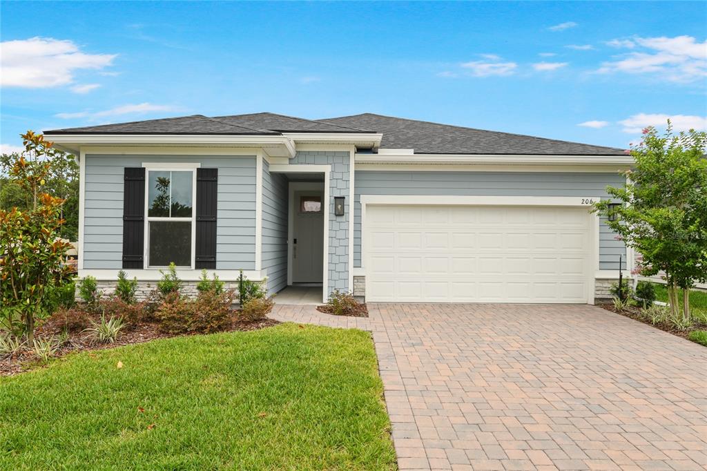 A single-story house with light blue siding, a two-car garage, and a paved driveway — 206 ENCLAVE AVENUE, PALM COAST, FL