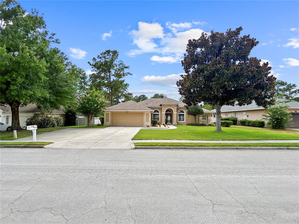 A single-story suburban house with a tan exterior, a two-car garage, and a large front lawn — 2716 SW 20TH AVENUE, OCALA, FL