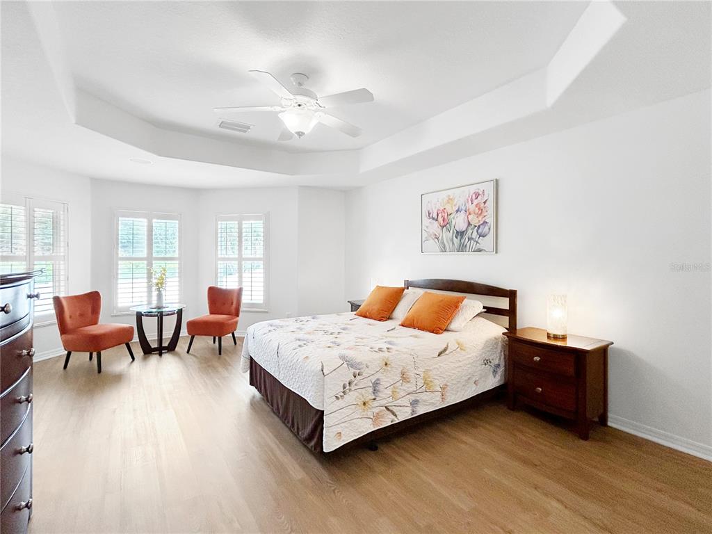 A bedroom features a bed, two orange chairs, a small table, and light wood flooring — 2716 SW 20TH AVENUE, OCALA, FL