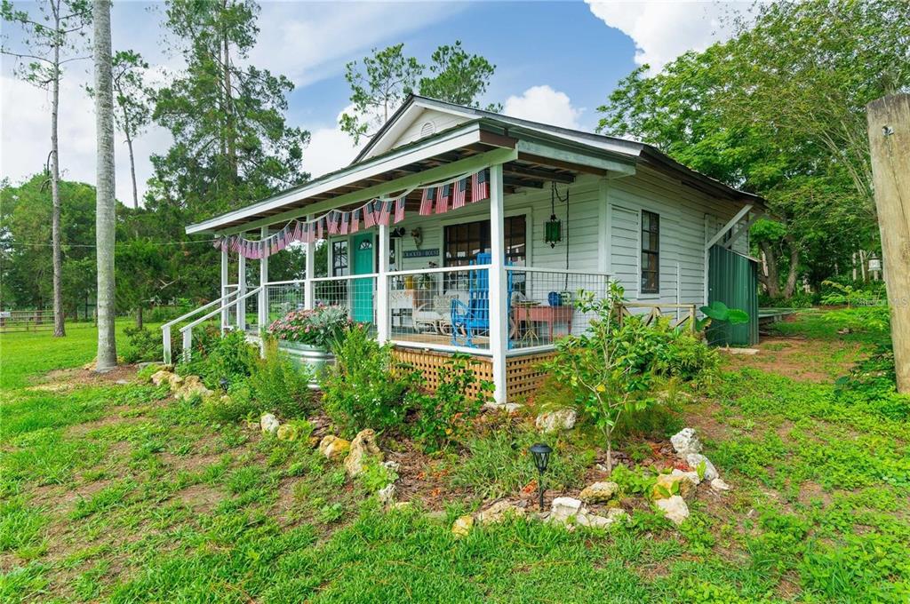 A white cottage with a covered front porch decorated with American flag bunting — 39425 WILDS ROAD, DADE CITY, FL