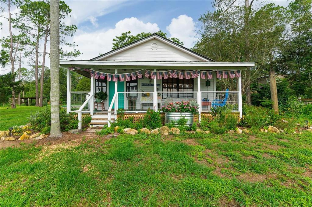 A white cottage with a covered front porch decorated with American flag bunting — 39425 WILDS ROAD, DADE CITY, FL