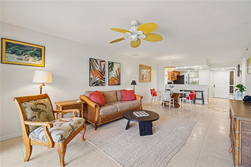 A living room with tile floors, a rattan sofa, a ceiling fan, and dining area — 3627 BAL HARBOR BOULEVARD UNIT 111, PUNTA GORDA, FL