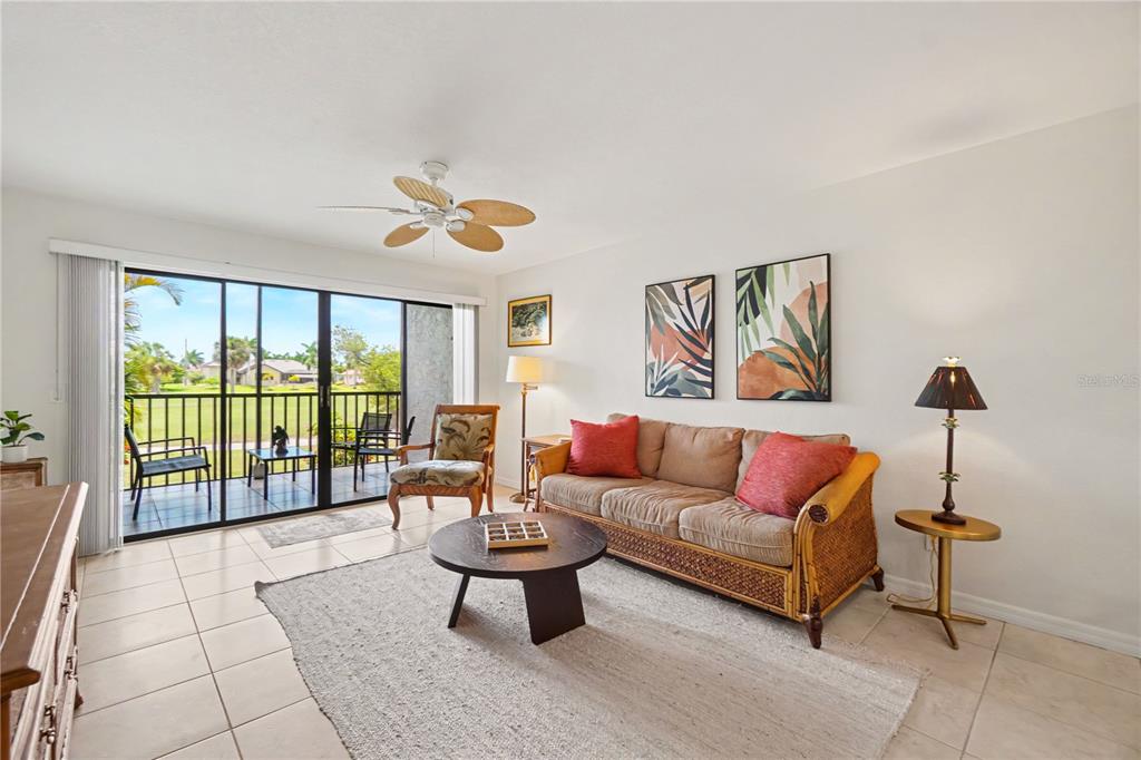 A living room features a wicker sofa, round coffee table, and sliding doors to a balcony — 3627 BAL HARBOR BOULEVARD UNIT 111, PUNTA GORDA, FL