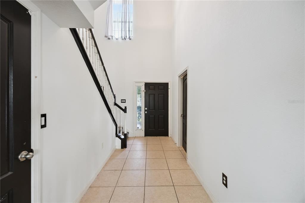 A brown front door and a wooden chair sit on a covered concrete porch — 5170 PRESERVE BOULEVARD, ST CLOUD, FL