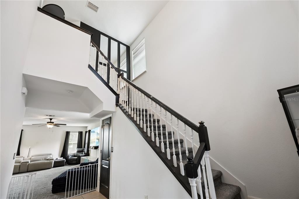 An entryway features a tiled floor, a black front door, and a staircase with railing — 5170 PRESERVE BOULEVARD, ST CLOUD, FL