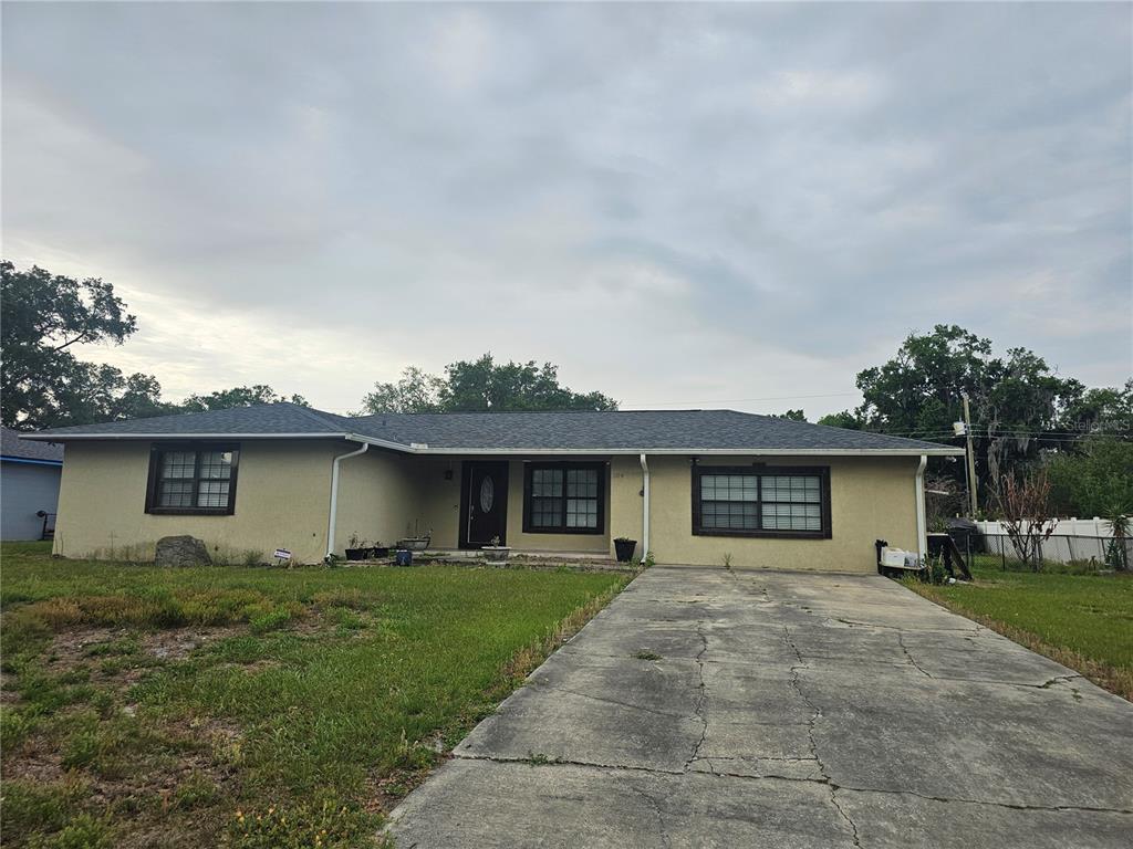 A single-story house with a beige stucco exterior, dark window trim, and a concrete driveway — 204 JENNY WAY, LAKELAND, FL