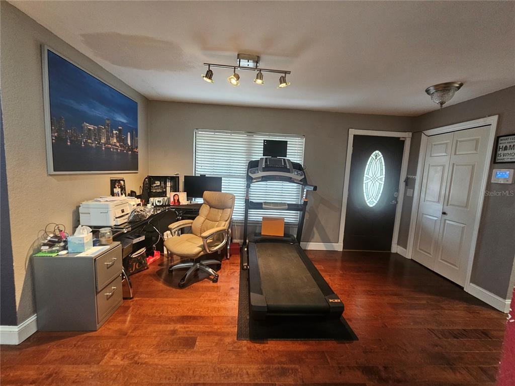 A room with hardwood floors, a desk, a treadmill, and a front door — 204 JENNY WAY, LAKELAND, FL