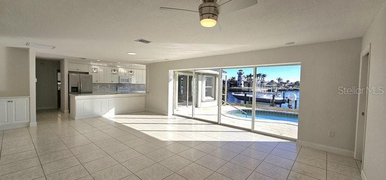 An open-concept kitchen and living area with tile floors overlooks a pool and canal — 418 MEDICI COURT, PUNTA GORDA, FL