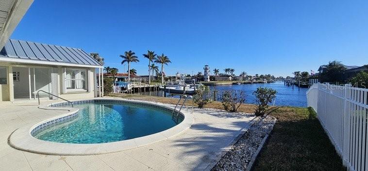 A swimming pool sits on a patio next to a house overlooking a canal — 418 MEDICI COURT, PUNTA GORDA, FL