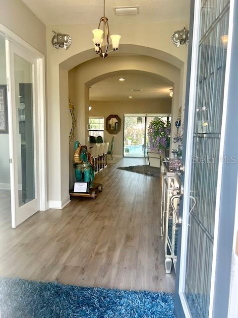 An entryway with light wood flooring leads through an arched hallway toward a living area — 2667 NORTHWOOD PARK STREET, VALRICO, FL