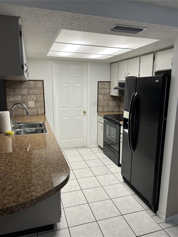 A kitchen features granite countertops, white cabinets, black appliances, and a tiled floor — 4813 DOGWOOD STREET, NEW PORT RICHEY, FL